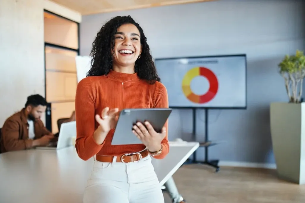 A smiling professional with a tablet beside a dashboard display